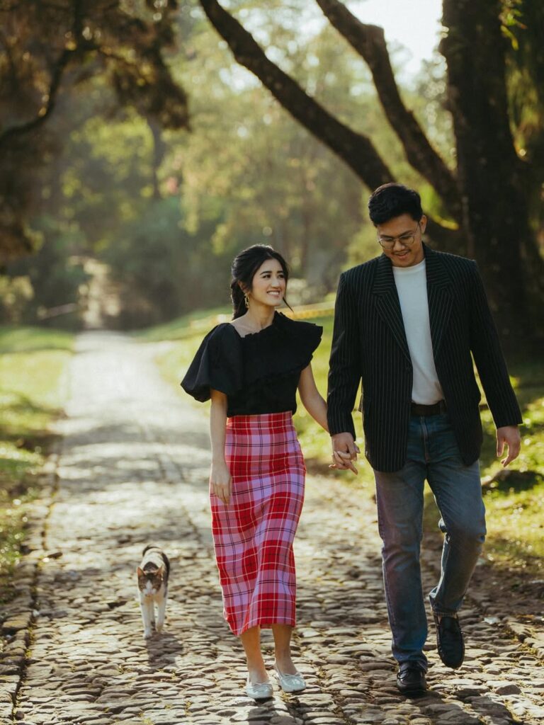 Pasangan prewedding berjalan bergandengan di jalan setapak berbatu di Kebun Raya Cibodas saat sunrise. source: sabilasyarafina